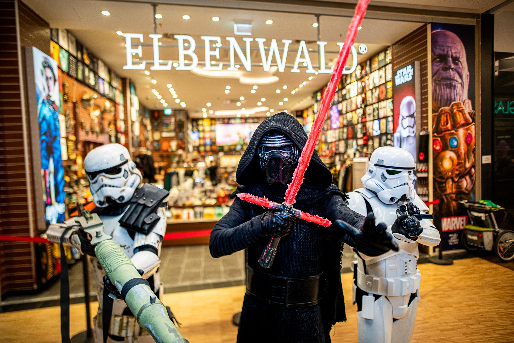 Das Foto zeigt drei Cosplayer in Kostümen aus dem FIlm Star Wars. Sie posieren für dem Eingang zu einem Elbenwald Store.