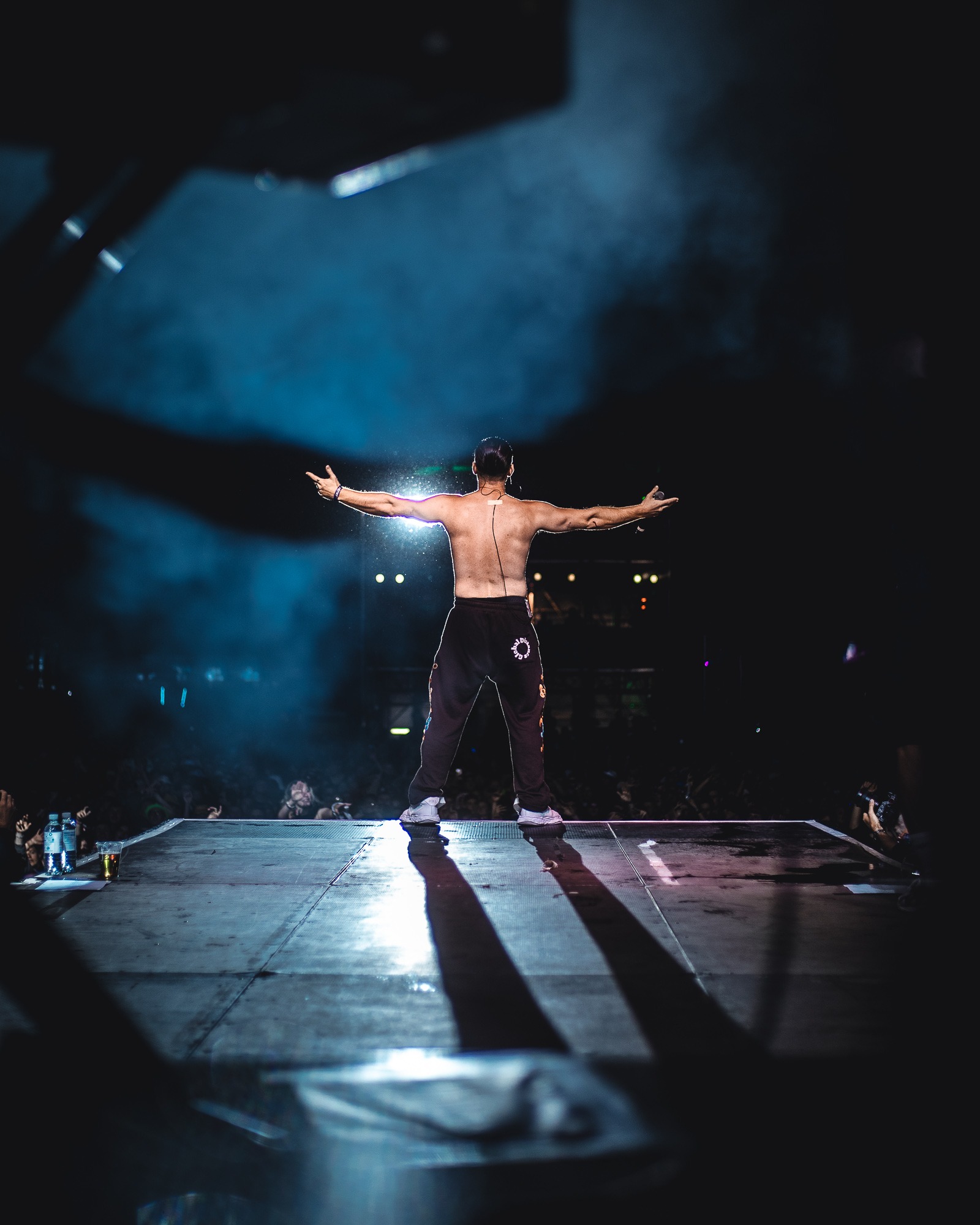 Das Foto zeigt den Sänger Bausa mit Rücken zu Kamera wie er auf einer Bühne steht und von Scheinwerfern angeleuchtet wird.