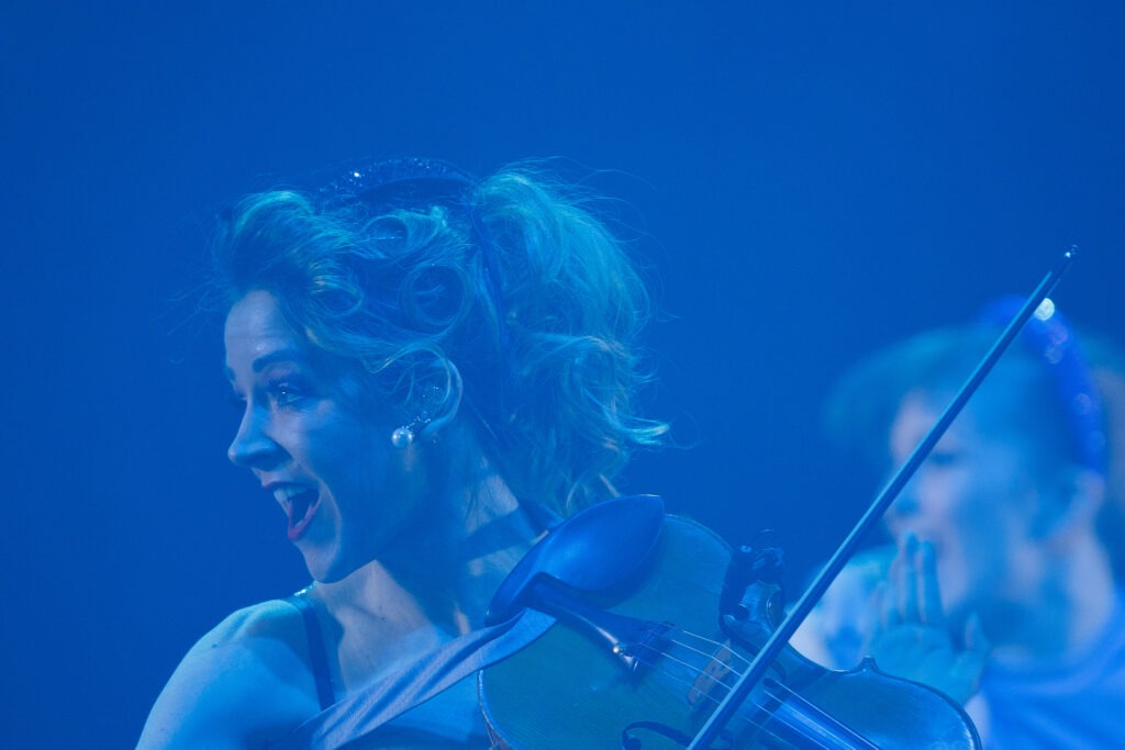 Eine Frau spielt Geige vor blauem Hintergrund.